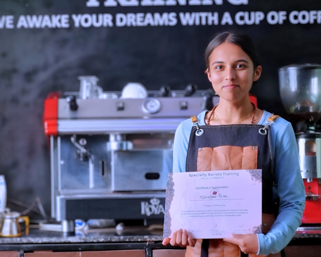 A close-up of a barista creating intricate latte art in a cup.